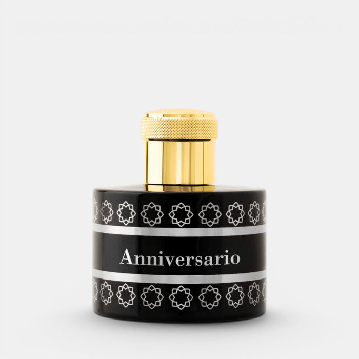 A cylindrical black bottle with a shiny gold cap, featuring a black label with white geometric patterns and the text 'Anniversary' in the center, set against a light gray background.