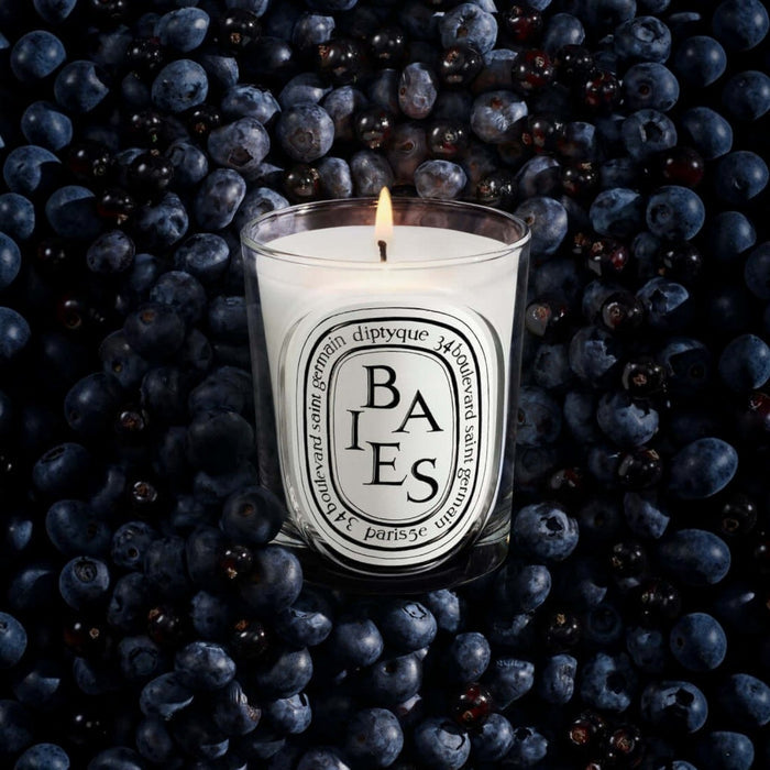 Shop Rescue Spa Baies candle in a glass vessel surrounded by a bed of fresh dark blackcurrants and blueberries