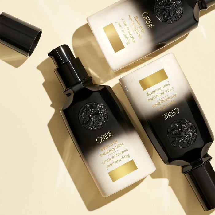 Shop Rescue Spa Oribe Balm d'Or Heat Styling Shield, a black and white bottle with gold accents, offering thermal protection for hair.