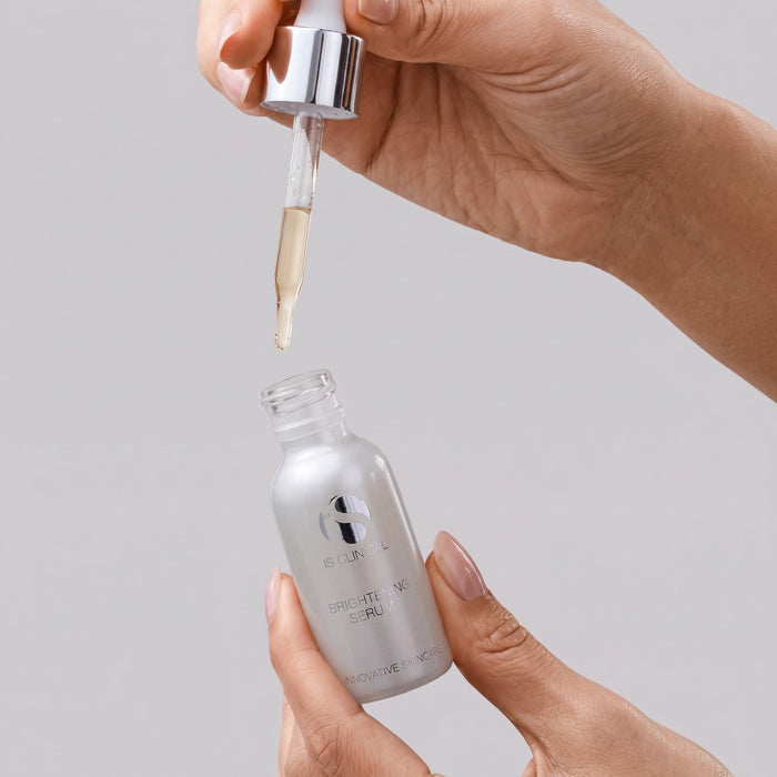 Shop Rescue Spa iS Clinical Brightening Serum in a silver bottle with a dropper being held by hands