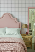 Bedroom with pink bedhead and door frame against charcoal check wallpaper
