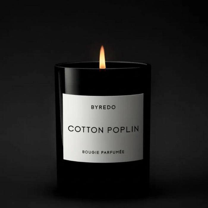 Shop Rescue Spa Cotton Poplin candle in a black glass jar with a white label, lit flame.
