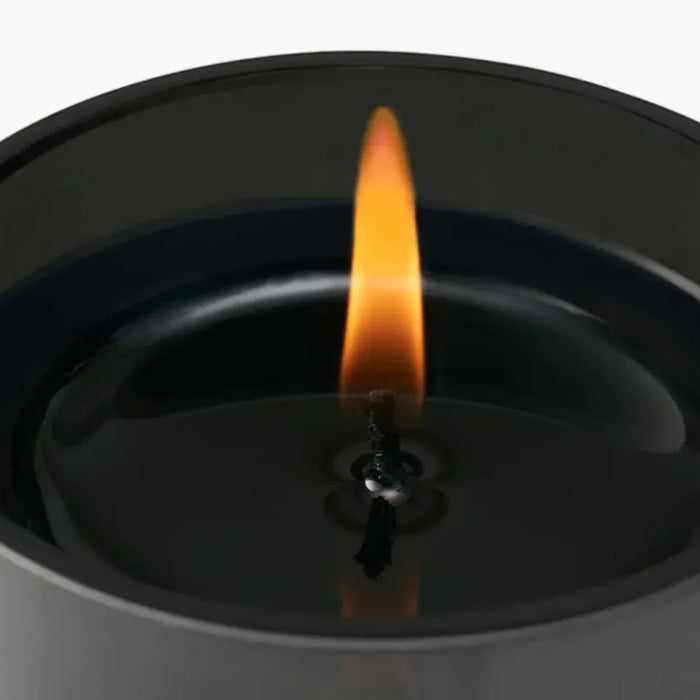 Shop Rescue Spa Cotton Poplin candle in a black reusable glass jar with a lit flame. Scent notes of chamomile, linen, cedar, and musk.