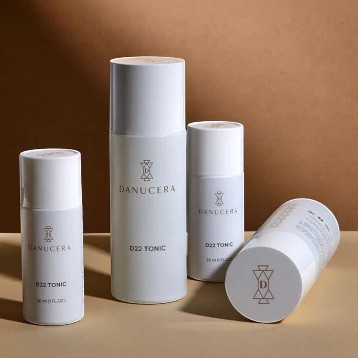 Shop Rescue Spa Danucera D22 Tonic exfoliating facial toner bottles in various sizes against a tan background.