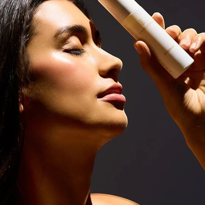 Shop Rescue Spa D7 Serum held by a woman with glowing, radiant skin, highlighting the protective golden elixir.