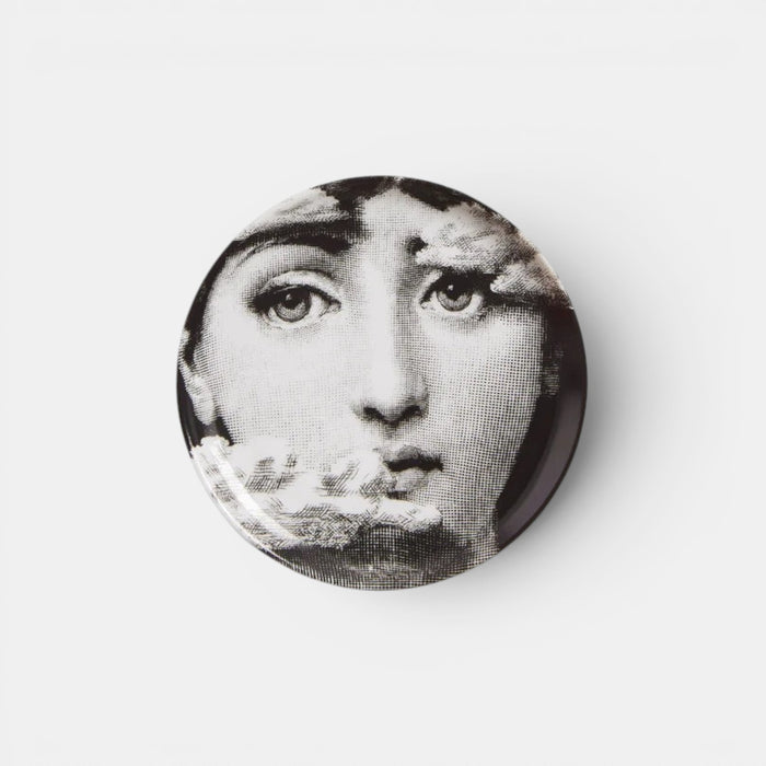 Circular decorative plate with a black and white face design on a white background