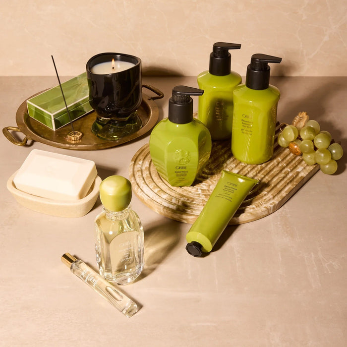 Shop Rescue Spa Desertland Eau De Parfum, a clear glass bottle with a green cap and gold accents, alongside other Oribe Desertland products.