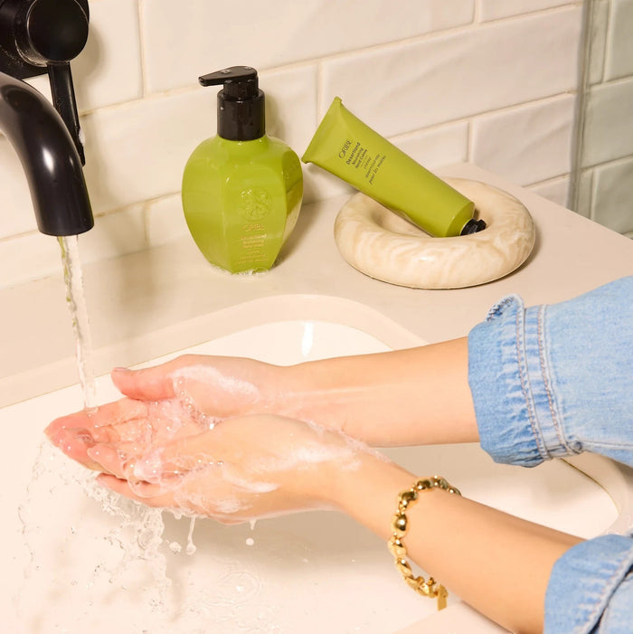 Shop Rescue Spa Oribe Desertland Revitalizing Hand Wash in a green pump bottle and tube, with hands being washed.