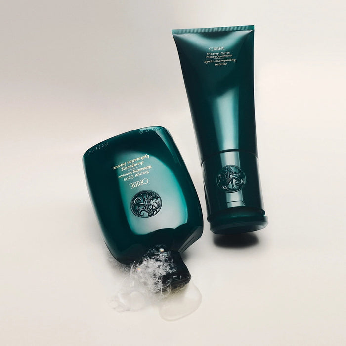 Shop Rescue Spa Oribe Eternal Curls Intense Conditioner and Moisturizing Shampoo in deep teal bottles. Conditioner tube upright, shampoo bottle tipped with foam.
