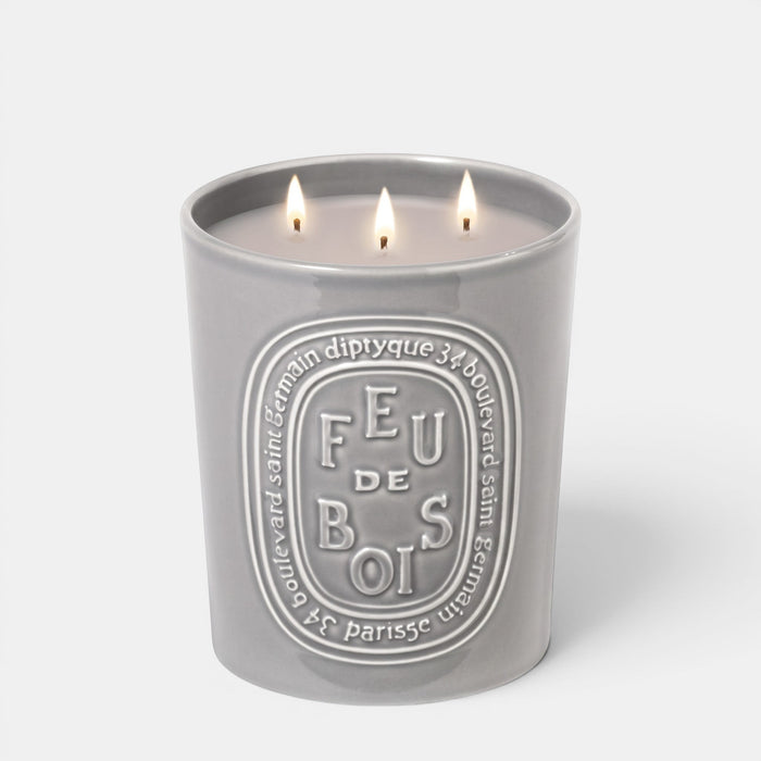 Shop Rescue Spa Feu De Bois scented candle in a grey ceramic vessel with three lit wicks and embossed branding.