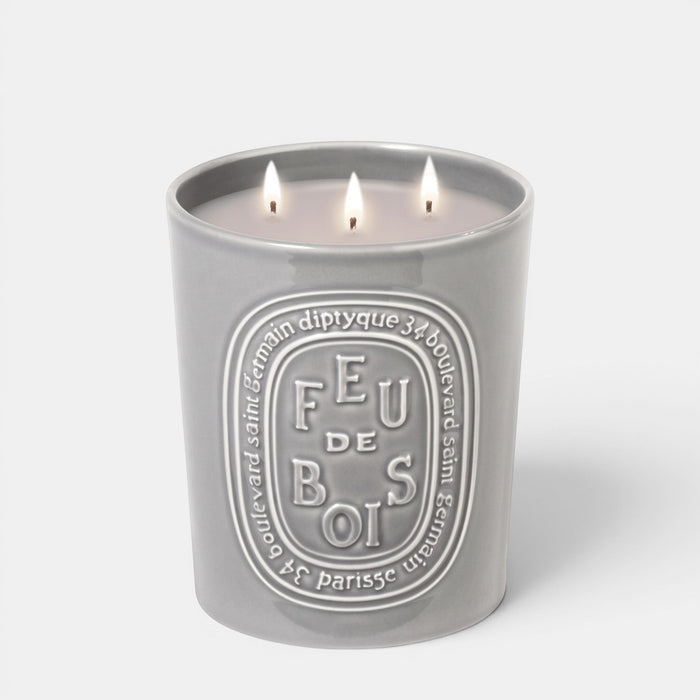 Shop Rescue Spa Feu De Bois scented candle in a grey ceramic vessel with three lit wicks and embossed branding