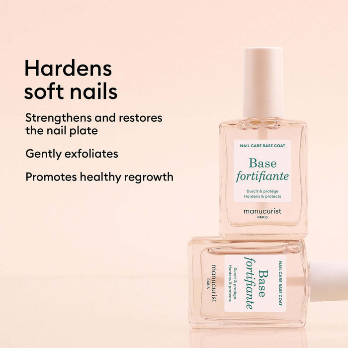 A bottle of manucurist Base fortifiante nail care base coat, stacked on top of another bottle, with promotional text on a soft peach background.