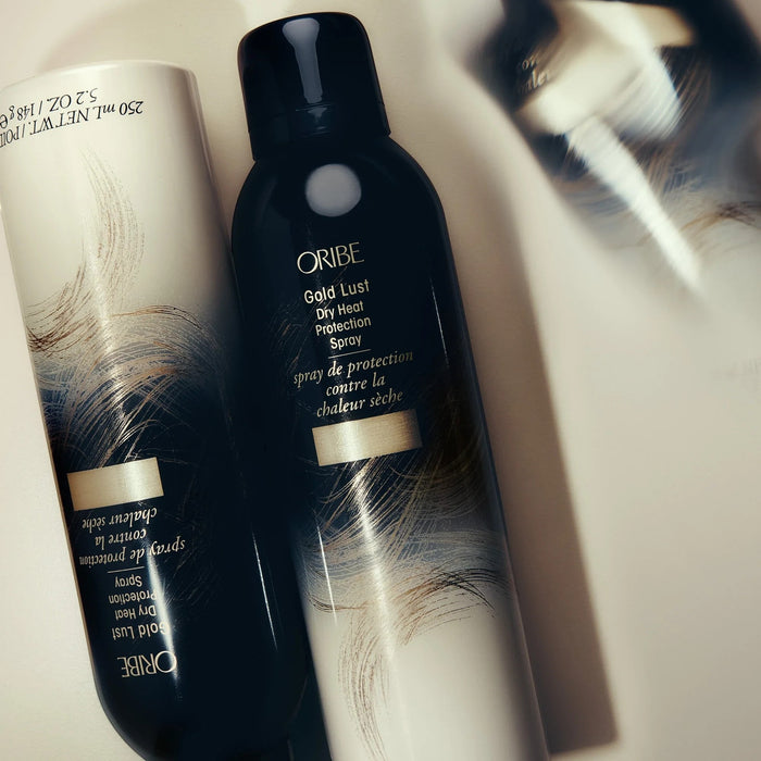 Shop Rescue Spa Oribe Gold Lust Dry Heat Protection Spray, a dark bottle with gold and white abstract design, protects hair from heat.