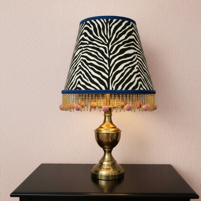 Zebra print lampshade on black table with pink Buckingham Anaglypta wallpaper