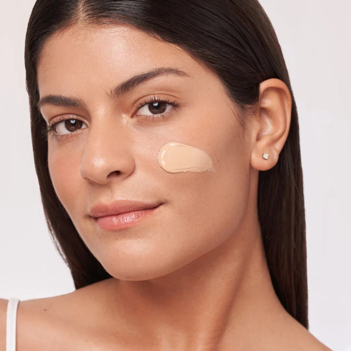 Shop Rescue Spa HydraTint Pro mineral sunscreen applied as a glowing tint on a woman's cheek for sun protection.