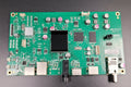 Green electronic circuit board with various components on a gray background