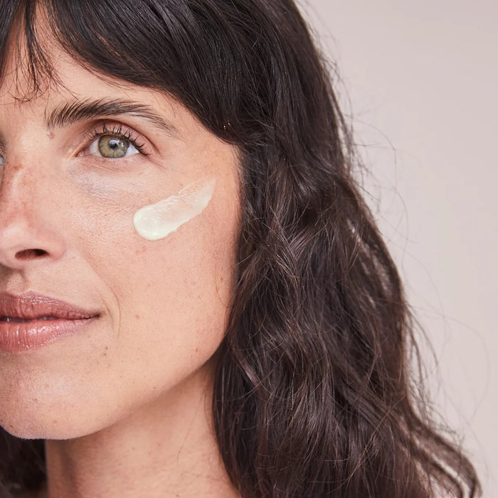 Shop Rescue Spa Renewal Retinol 0.5 serum applied as a cream dab on a woman's cheek for skin texture improvement