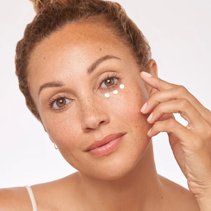 Shop Rescue Spa Restorative Eye Complex applied as small dots under the eye of a woman to reduce dark circles