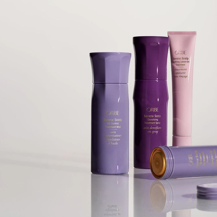 Oribe Serene Scalp Soothing Leave-On Treatment in a pink tube, with purple scalp treatments.