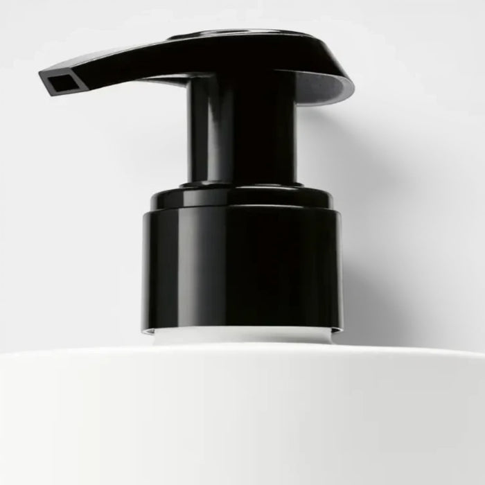 Shop Rescue Spa Suede Hand Lotion with black pump dispenser on white bottle. Woody, aromatic scent.