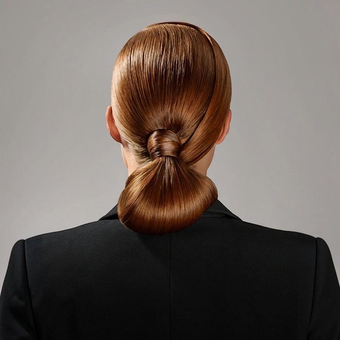 Shop Rescue Spa Superfine Strong Hair Spray on a model with auburn hair styled in a sleek, low bun with a knot detail.