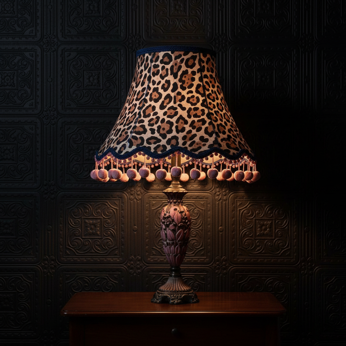 Large animal print lampshade with visible pink pom poms on tassels