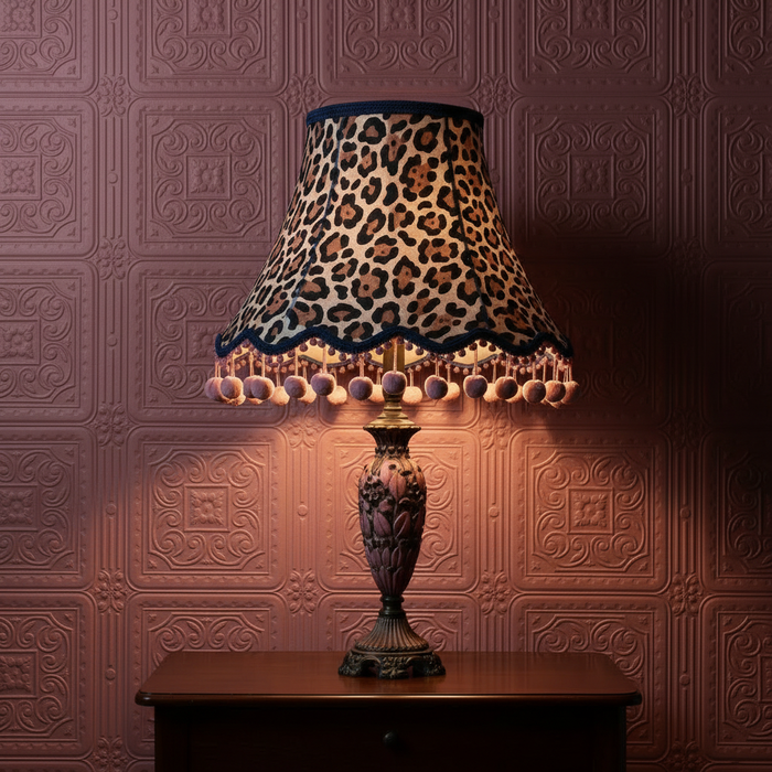Large animal print lampshade with pink pom poms on pink Anaglypta Turner Tile wallpaper