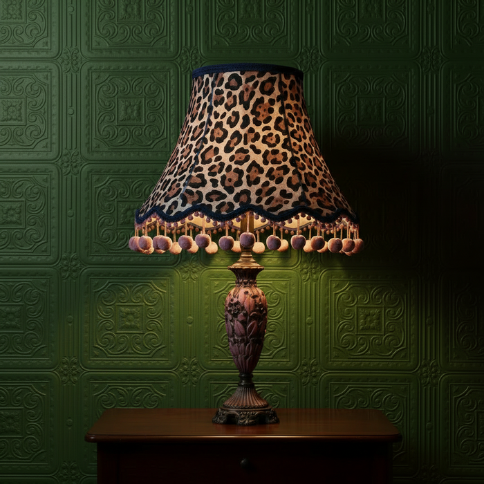 Large animal print lampshade with pink pom poms on dark green Anaglypta Turner Tile wallpaper