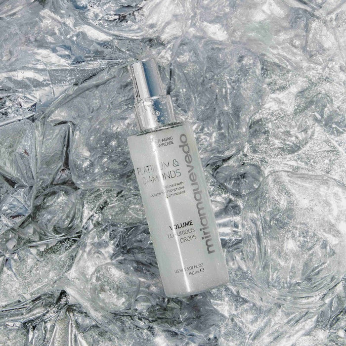 Shop Rescue Spa Volume Luxurious Drops hair mist bottle on a reflective silver crinkled background.