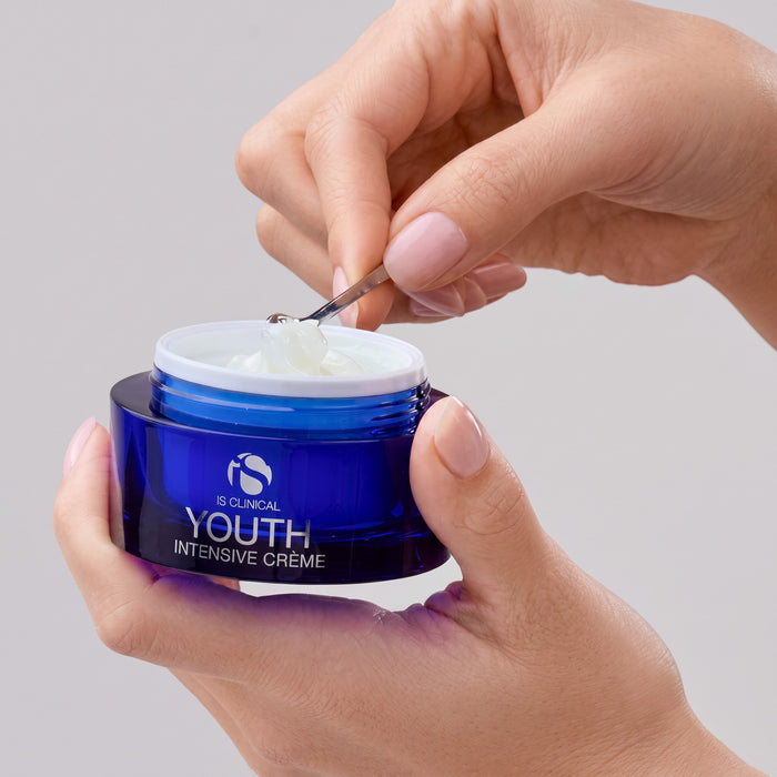 Shop Rescue Spa iS Clinical Youth Intensive Creme in a blue jar being scooped with a small metal spatula